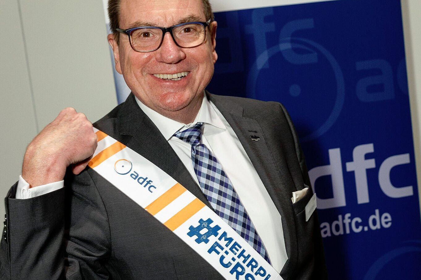 Der ADFC-Bundesvorsitzende Ulrich Syberg hat aus dem Absprerrband der Kampagne MehrPlatzFürsRad eine Schärpe gemacht.