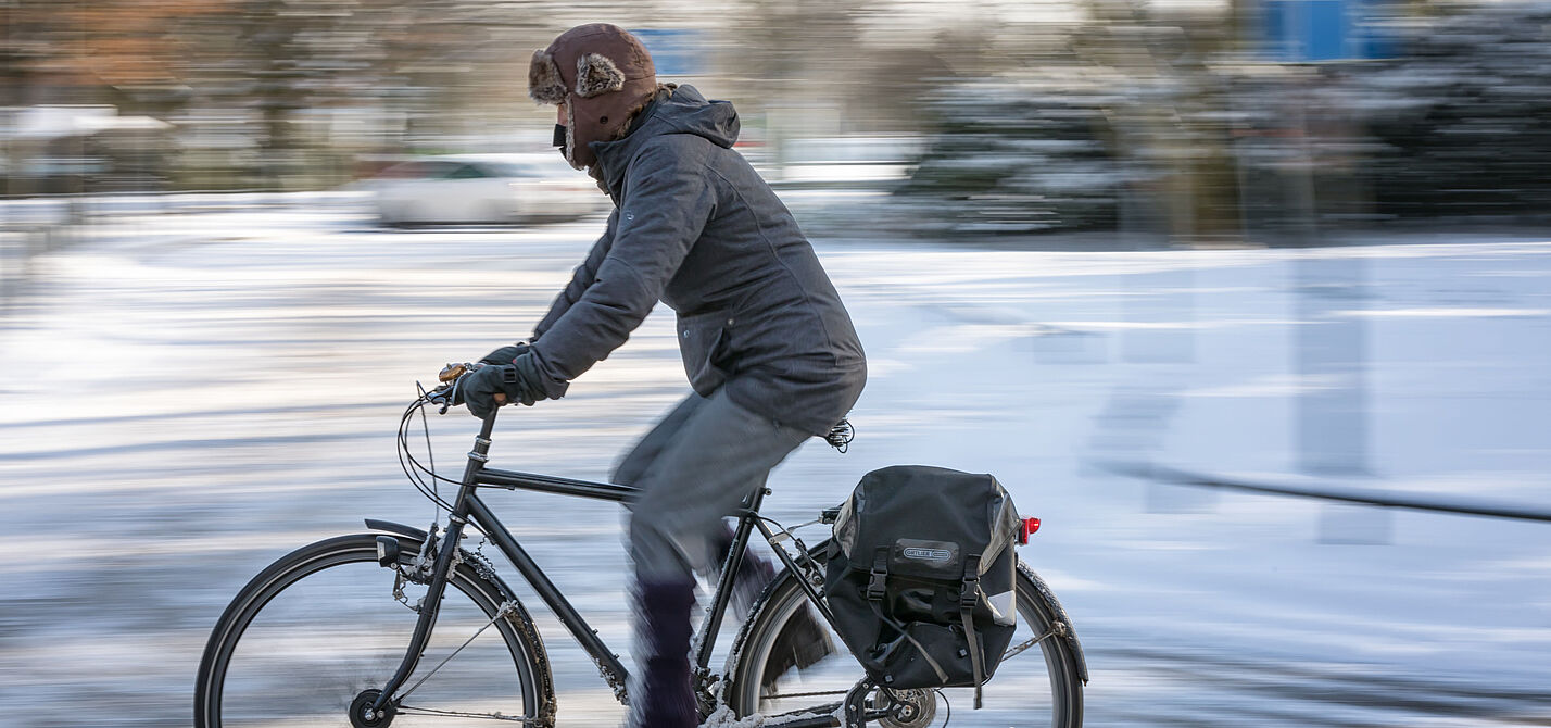 Radfahren kann auch im Winter Spaß machen.  Mann fährt auf ungeräumten Radweg im Winter