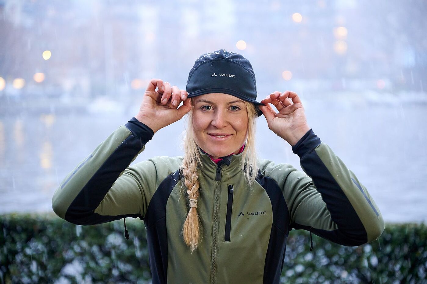 Helmmütze Eine Frau in Radkleidung setzt sich eine Helmmütze auf.